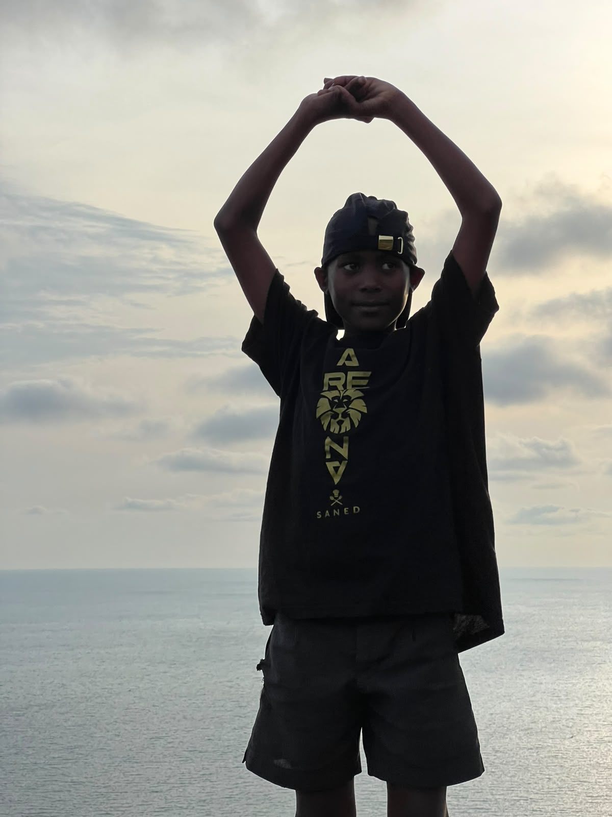Niño del proyecto de Asociación Arena celebrando frente al mar