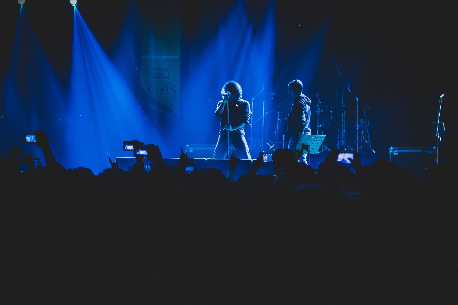Concierto con público iluminado de azul en un evento cultural